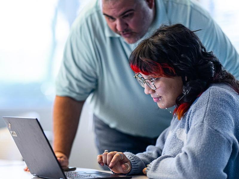 a person and person looking at a laptop